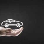 A hand is shown holding the outline of a car on a dark background.