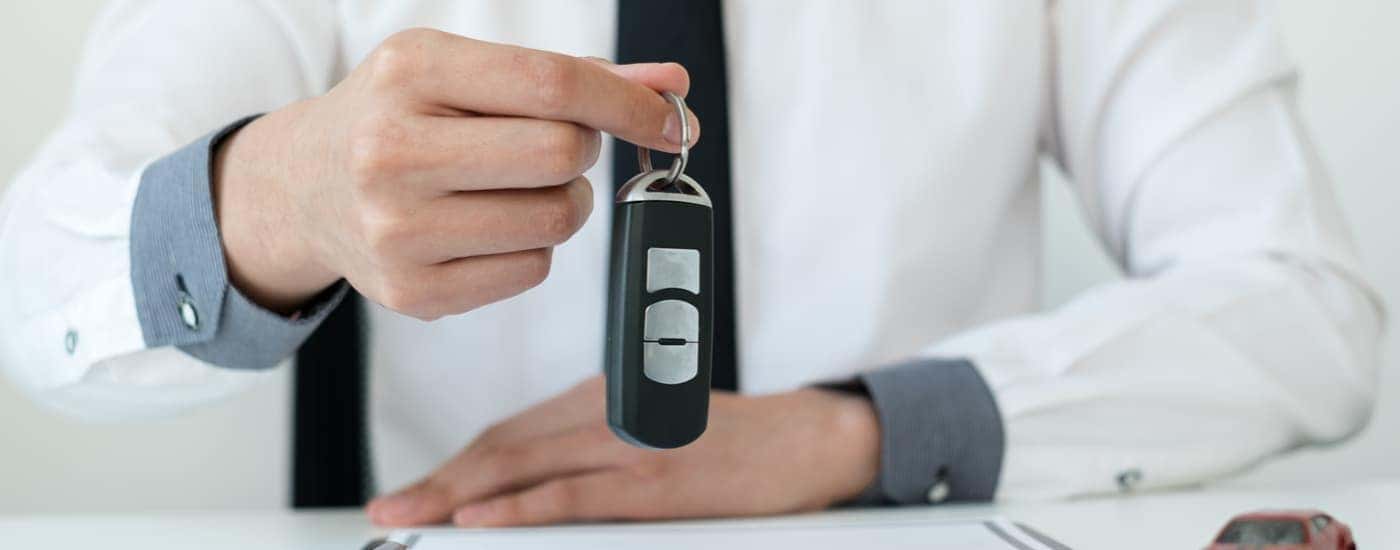 A salesman is shown holding a car key.