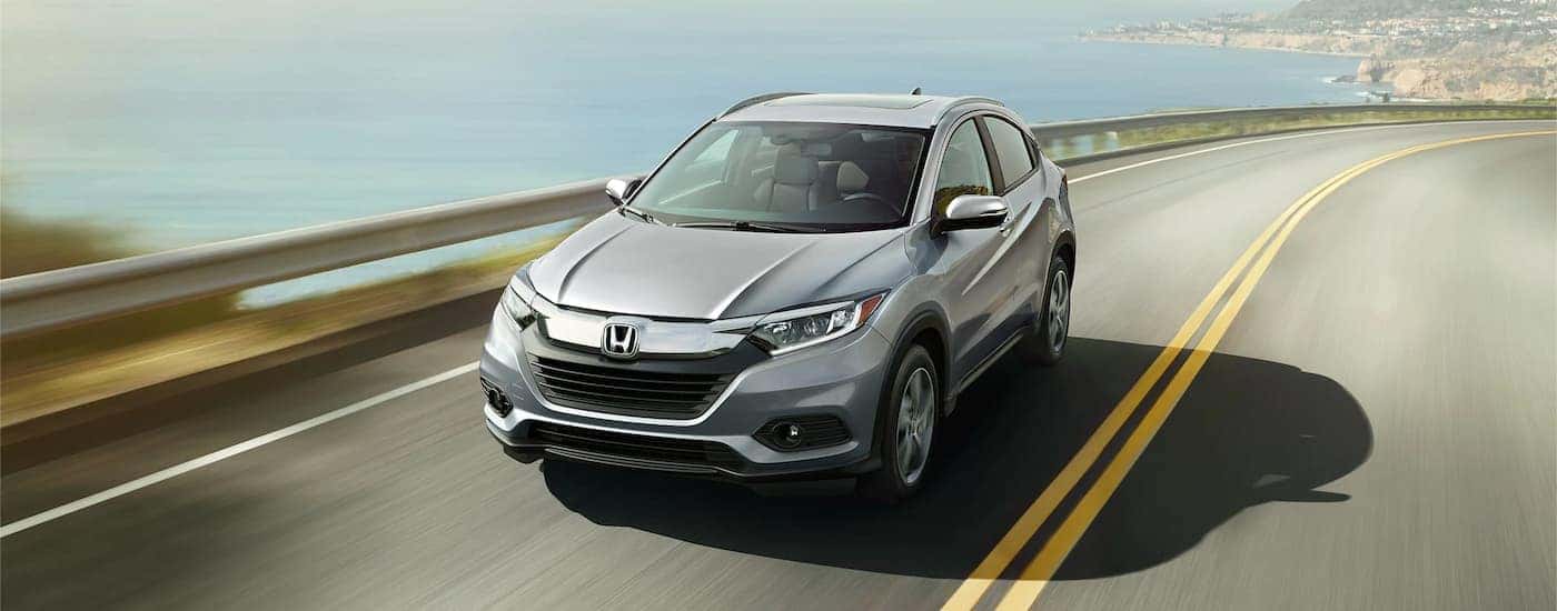 A silver 2022 Honda HR-V is shown driving down a highway near a body of water.