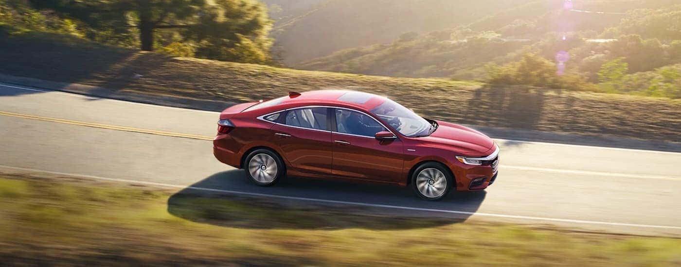 Side view of a red 2020 Honda Insight driving on an open road
