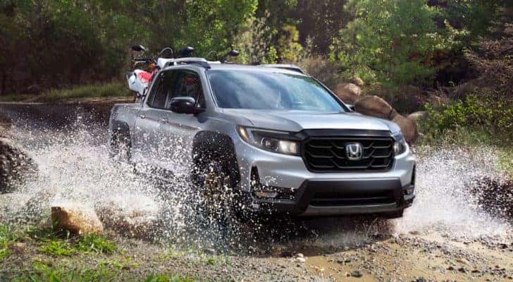 Front view of a silver 2022 Honda Ridgeline Sport off-roading through a small river