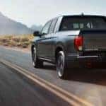A grey 2020 Honda Ridgeline RTL-E is shown from the rear driving on an open road.