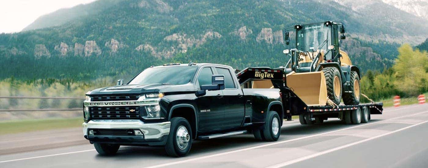 Front angled view of a black 2020 Chevy Silverado 3500 HD towing a loader