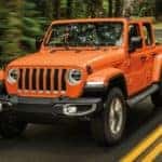 An orange 2022 Jeep Wrangler is shown from the front driving on an open road after looking a used Jeep Wranglers for sale.