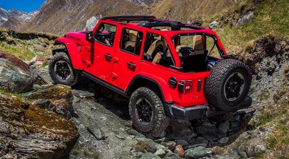 A red 2020 Jeep Wrangler Unlimited driving up a rocky hill