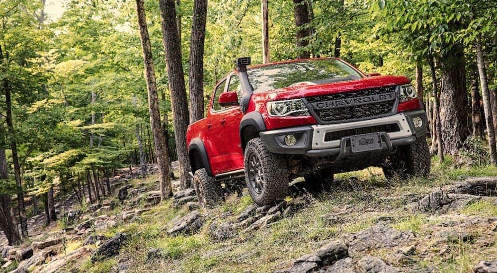 Front view of a red 2020 Chevy Colorado driving on a rocky woods path
