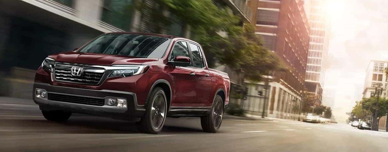 A red 2020 Honda Ridgeline RTL-E is shown driving on a city street.