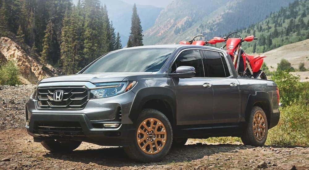 A grey 2022 Honda Ridgeline is shown from the front at an angle while loaded with dirt-bikes.