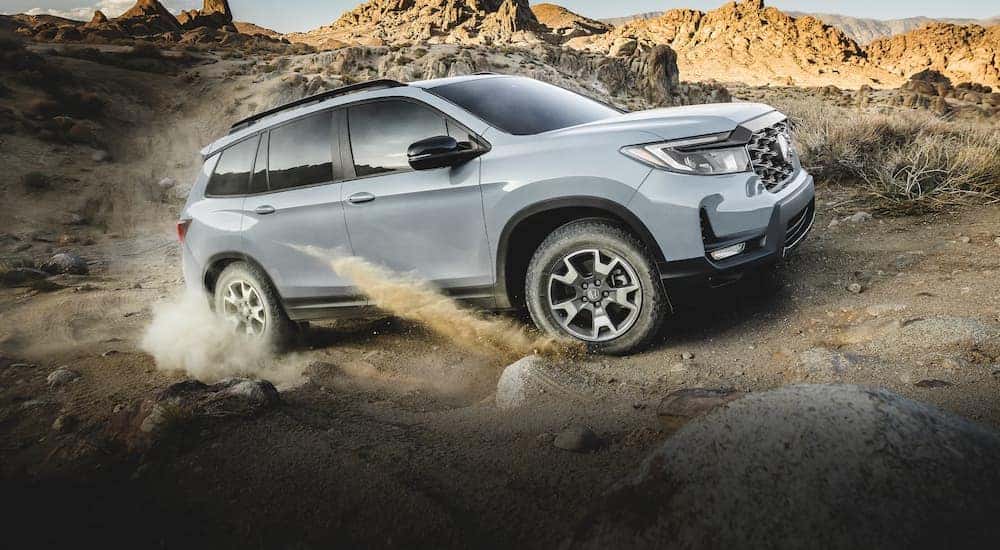 A grey 2022 Honda Passpot Trailsport is shown from the side while driving off-road.