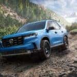 A blue 2023 Honda Pilot Trailsport is shown on a dirt trail.