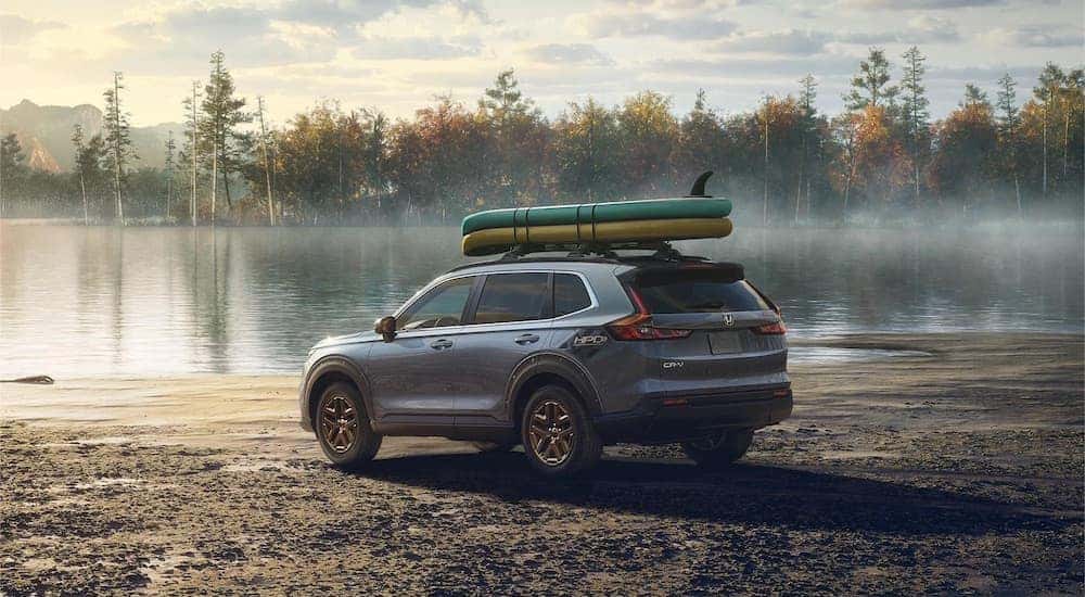 A grey 2023 Honda CR-V is shown from the rear at an angle while parked on a lakeshore after leaving a dealer that has a Honda CR-V for sale.