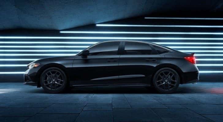 A black 2023 Honda Civic Si is shown in a front of lighted wall.