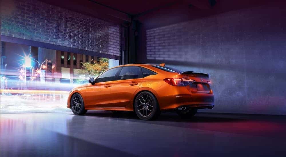 An orange 2023 Honda Civic Si is shown from the rear at an angle.