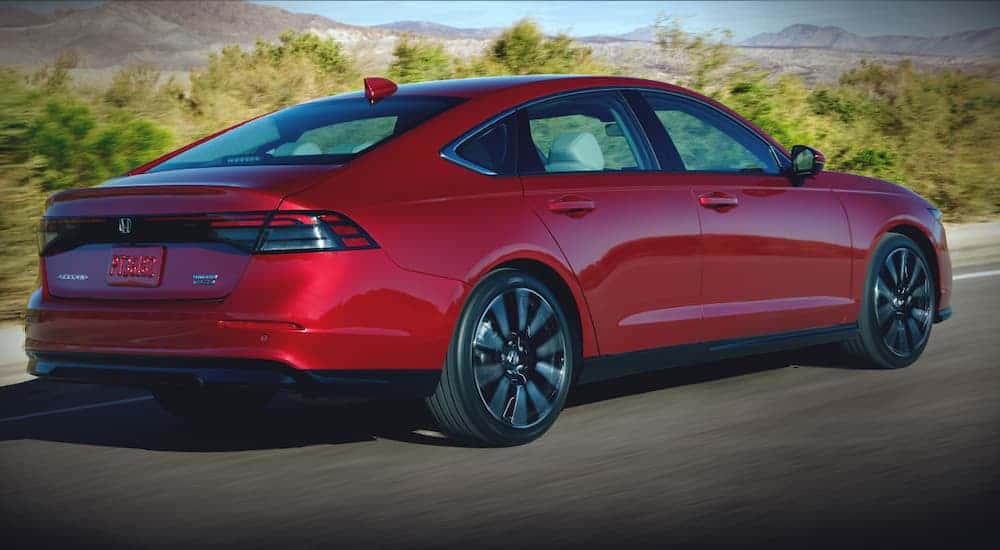 A red 2023 Honda Accord is shown from the rear at an angle after leaving a dealer that has cars for sale.