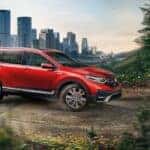 A popular Used Honda CR-V for sale, a red 2020 Honda CR-V, is shown driving on a dirt path.