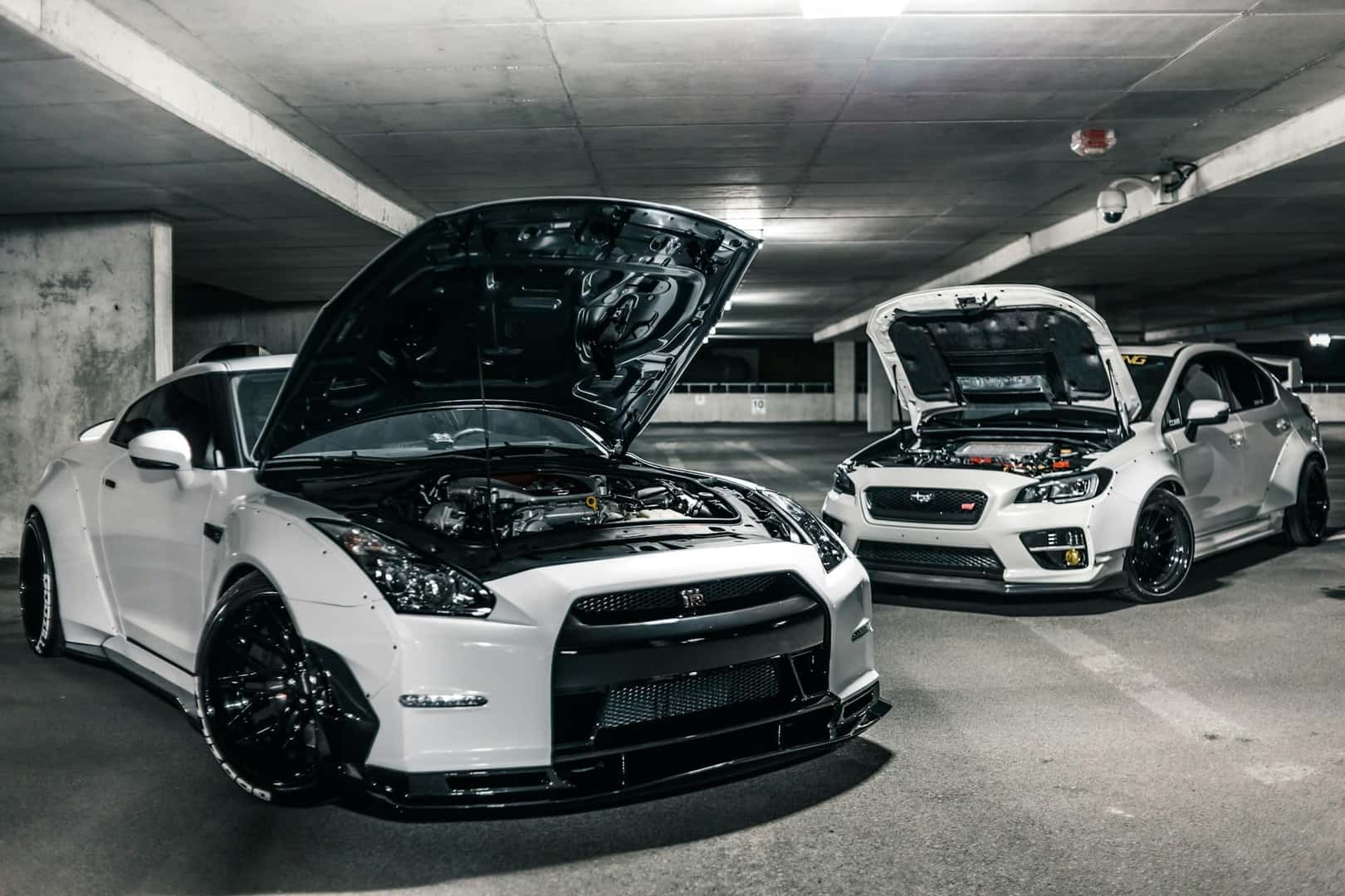 Two white cars with open hoods and visible engines