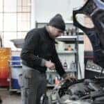 A vehicle repair technician inspecting a cars engine