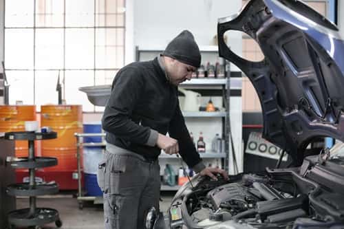 A vehicle repair technician inspecting a cars engine