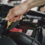 Hand checking oil dipstick in a car engine bay for maintenance and diagnostics