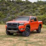 front view of orange nissan frontier parked outside on grass