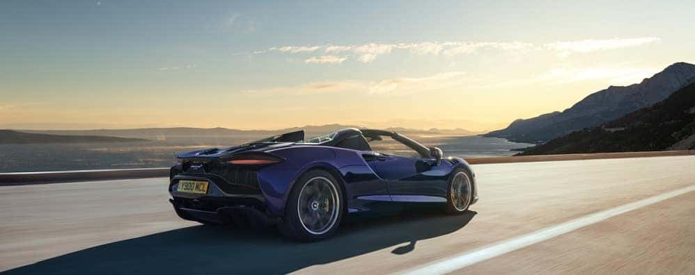 Purple McLaren Artura Spider driving on mountain highway