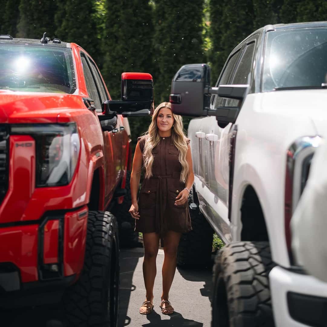 blonde woman standing between two trucks