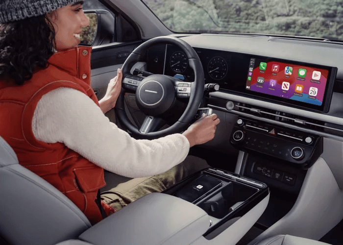 A driver inside a modern Hyundai Tucson, showcasing a sleek dashboard with a digital display and Apple CarPlay integration.