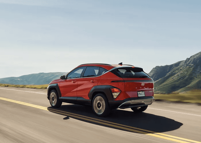 Red 2026 Hyundai Kona zooming on the highway.