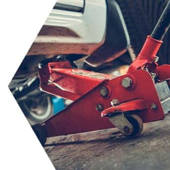 Basic Car Maintenance and Servicing Checklist | Performance Chevrolet | Red car jack lifting car upwards