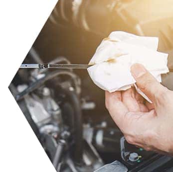 Basic Car Maintenance and Servicing Checklist | Performance Chevrolet | Mechanic checks car's oil level from dipstick