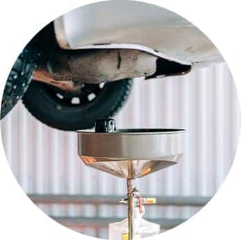Difference between synthetic oil & conventional oil at Performance Chevrolet | Oil catcher underneath a car on lift