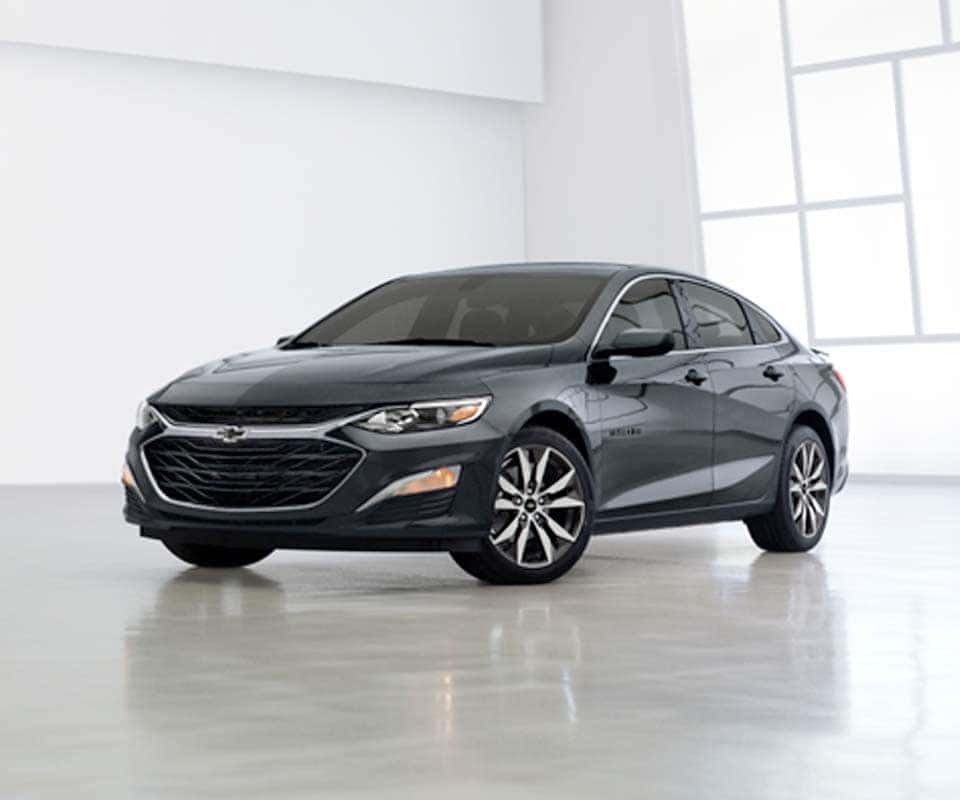 Performance Chevrolet is a Car Dealership near Poplar Branch, NC | 2021 Gray Chevrolet Malibu Sitting in White Showroom
