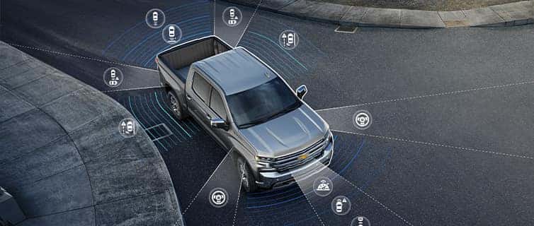 The 2022 Chevrolet Silverado 1500 at Performance Chevrolet | Silver Silverado with Graphics of Safety Features Surrounding it