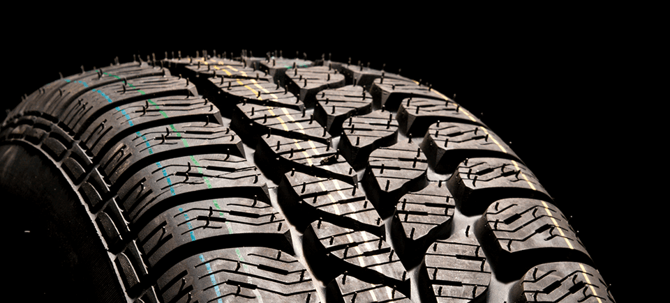 What is a Tire Rotation? at Performance Chevrolet | Close up look at a new tire with blue and green strips, in a black background
