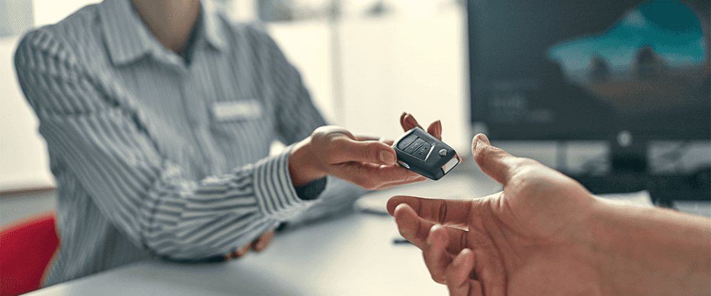 Vehicle Registration Taxes and Fees at Performance Chevrolet in Elizabeth City, NC | Sales person on the left side is handing over new car keys to a persons hand on the right side