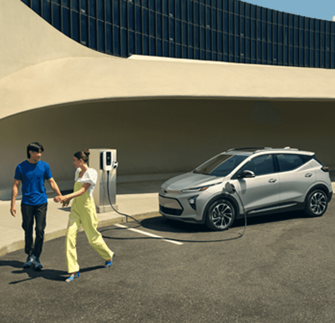 Chevrolet EV’s at Performance Chevrolet | Grey 2023 Chevrolet Bolt EV charging while a couple is walking away 
