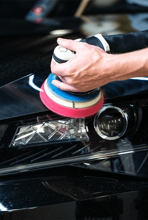 Accessories that help keep your Chevrolet protected at Performance Chevrolet in Elizabeth City, NC | Person using a buffer tool to buff up car headlights on their black car