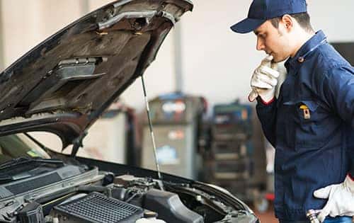 Mechanic looking into the front of a car