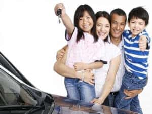 Familia latina feliz recibiendo su carro nuevo sin papeles