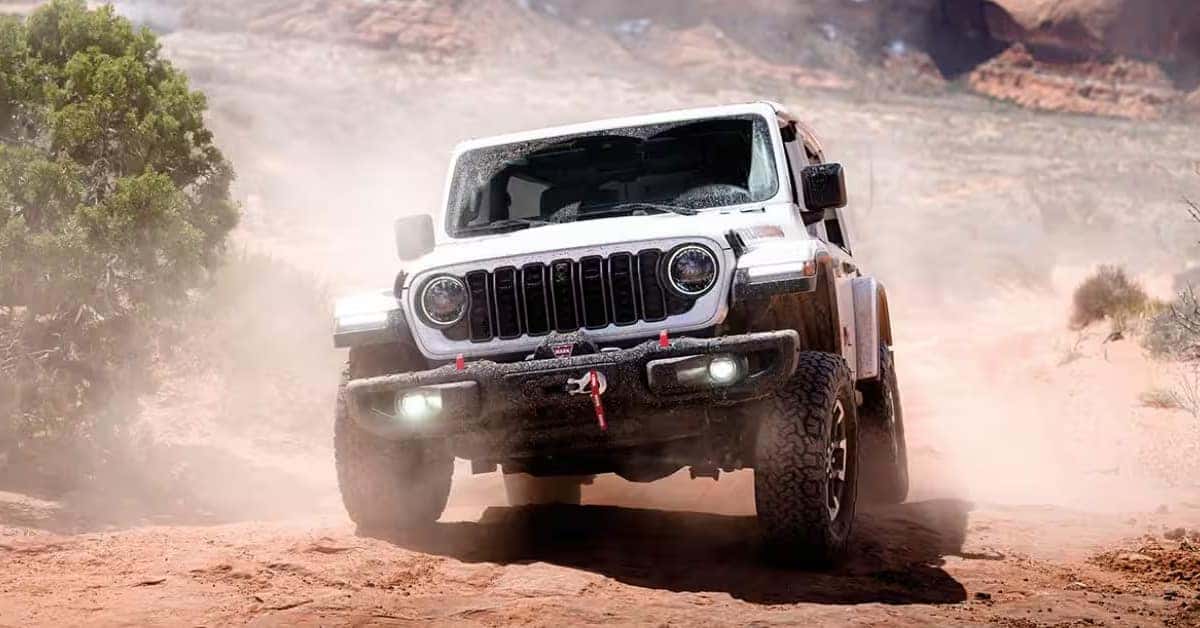 White Jeep Wrangler SUV tackling a rugged desert trail, showcasing off-road capability and adventure-ready performance.