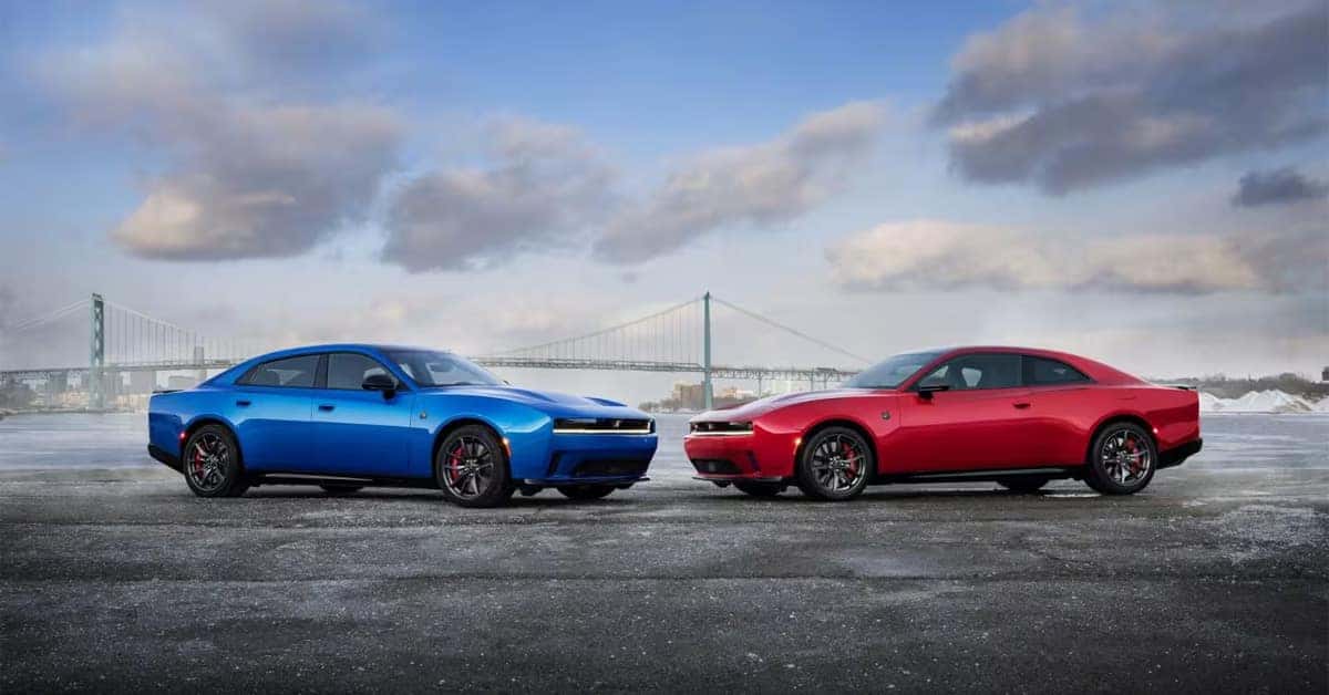 Dodge Charger parked near a waterfront with two red and blue performance sedans.