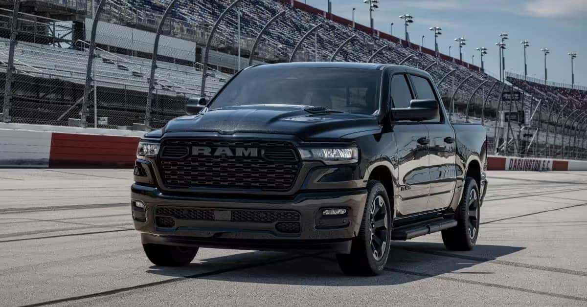 RAM 1500 pickup truck parked on a racetrack in front of grandstands.