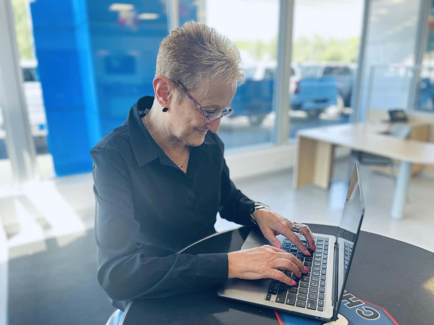 A girl sitting inside a dealership, looking at her computer.