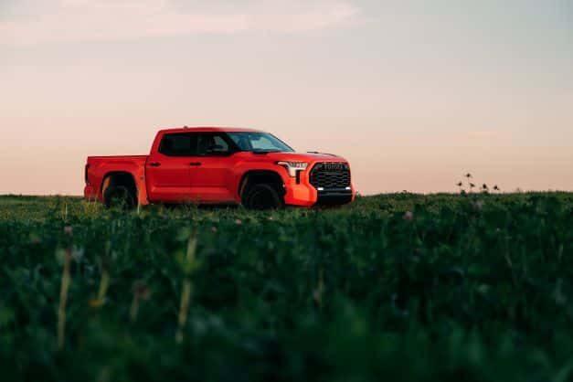 A solar orange Toyota Tundra parked in a field
