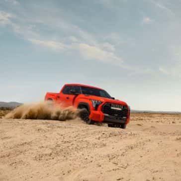 A Toyota Tundra in Solar Octane driving amongst the sand dunes