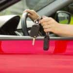 person sitting in a red car holding their key
