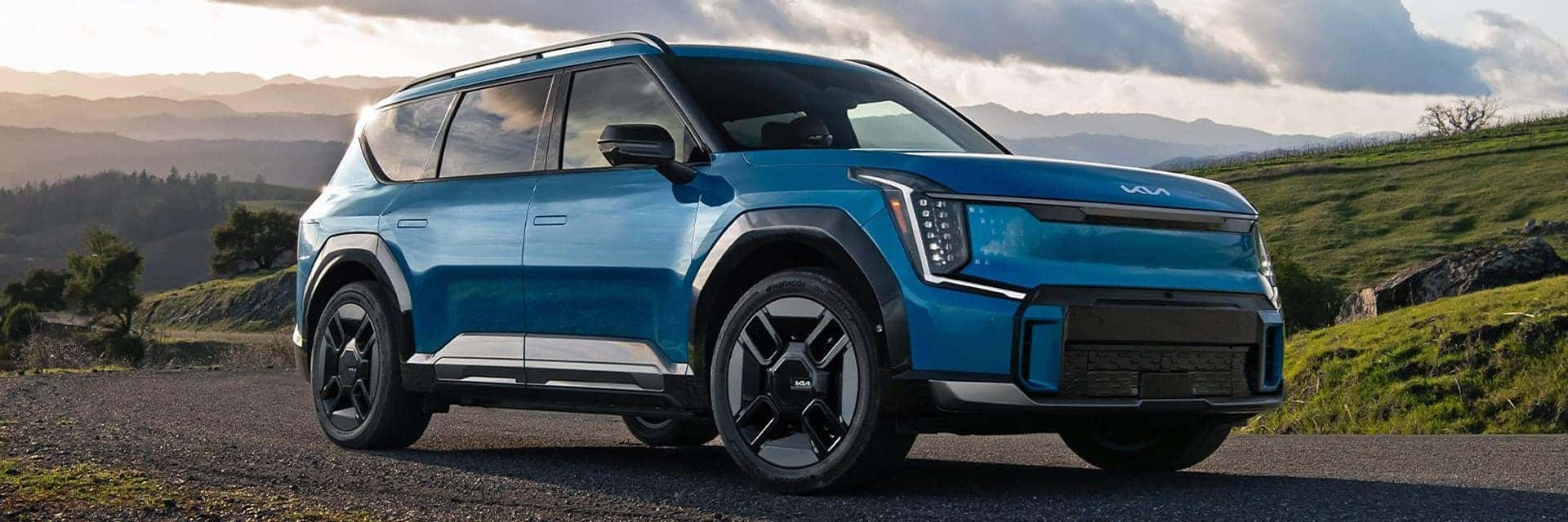 blue 2025 ev9 driving on road