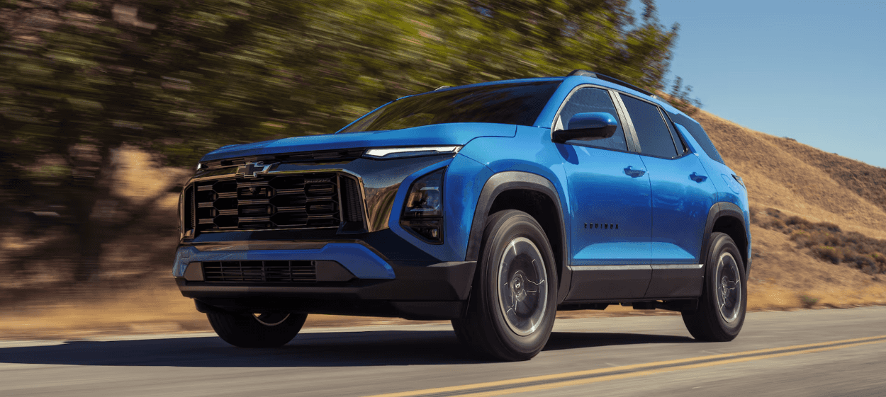 Blue 2027 Chevrolet Equinox driving down hilly road